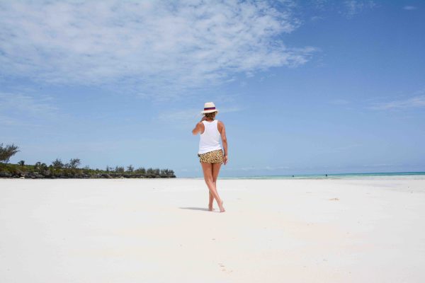 Tantra From behind, a woman stands on the beach capturing a moment with her camera.