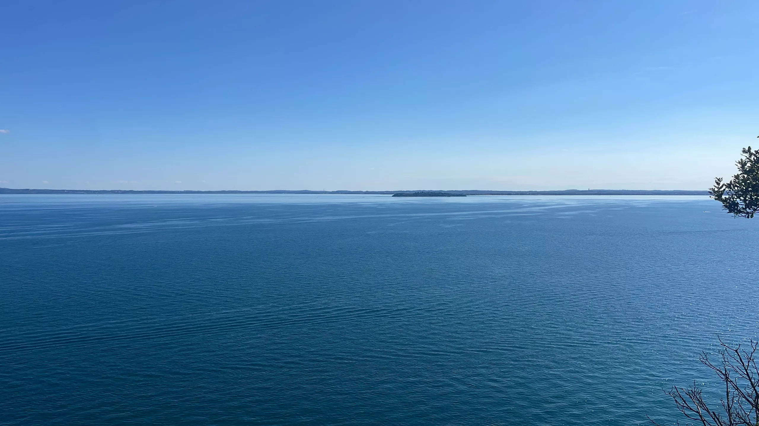 Tantra A peaceful view of Lake Garda with blue water and sunlight reflecting off the surface