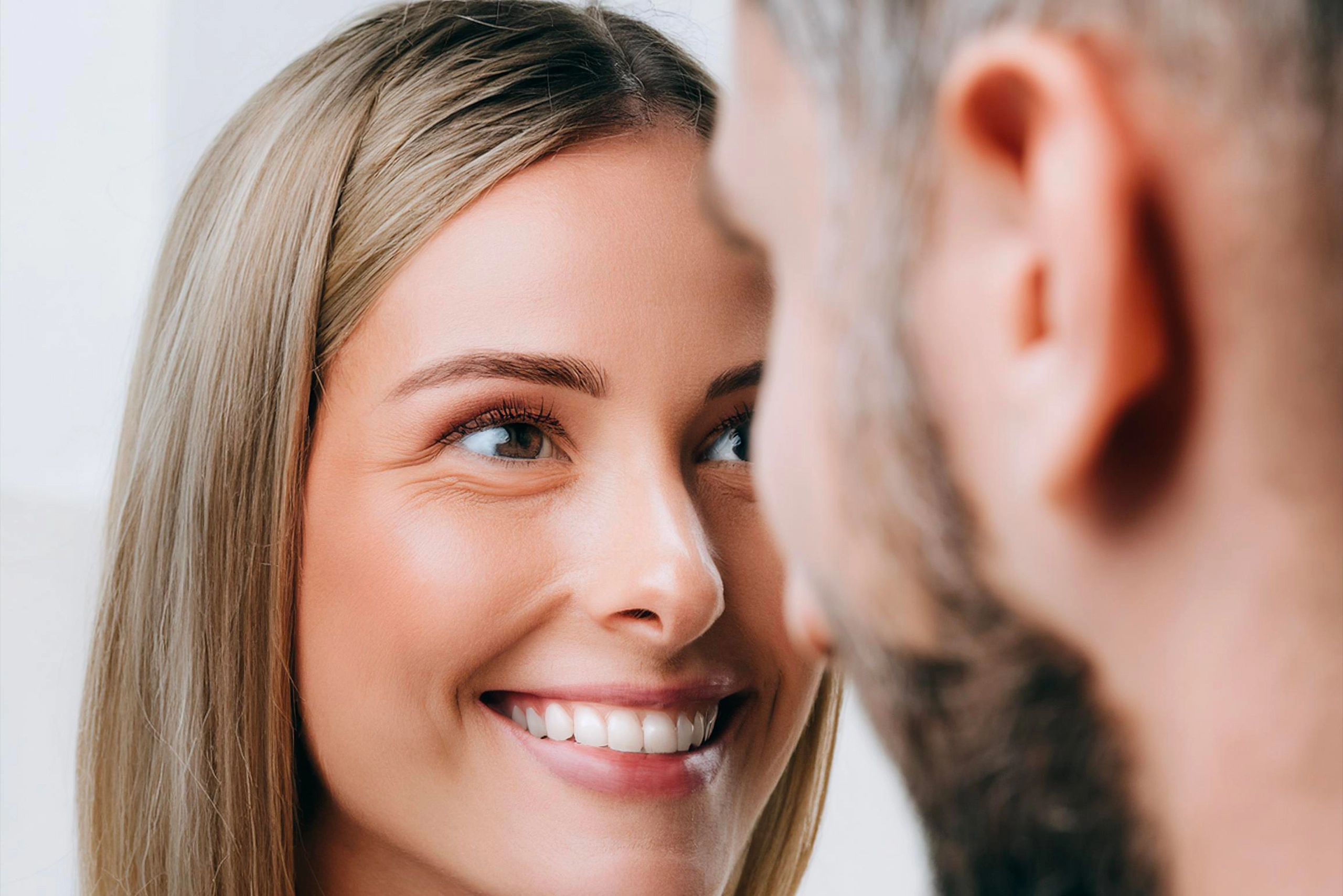 A woman intensely gazes at a man, expressing curiosity and interest. Their eyes meet, creating an atmosphere of connection and tension