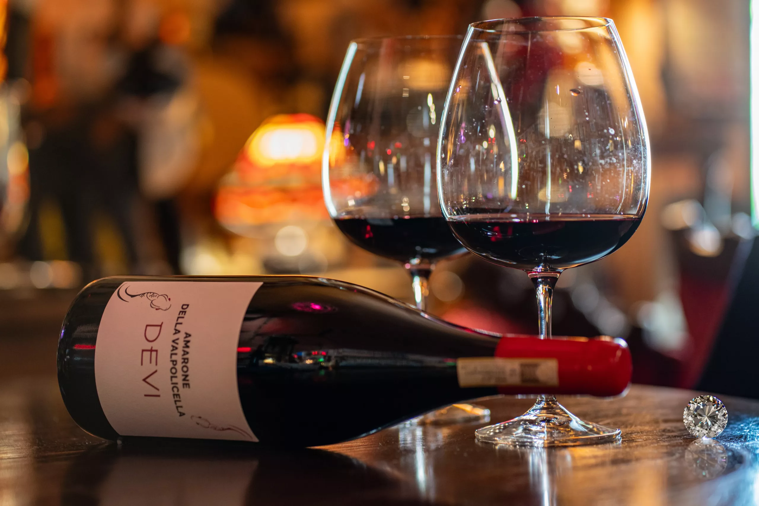 A bottle with two glasses, adorned by a small diamond, symbolizing elegance and shared moments of pure connection.