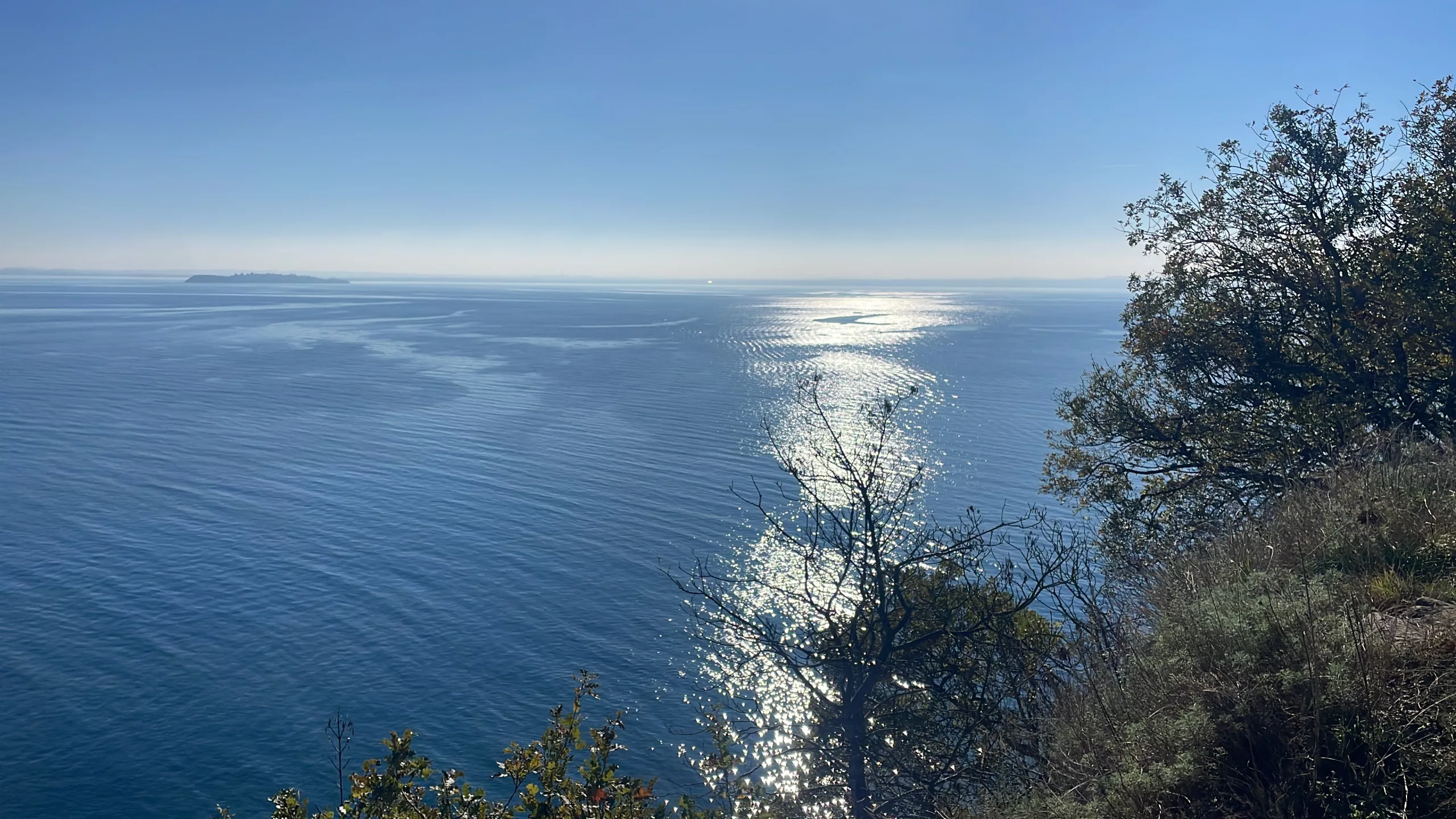 Lake Garda shimmering under the sunlight, with tranquil waters reflecting the vibrant colors of nature
