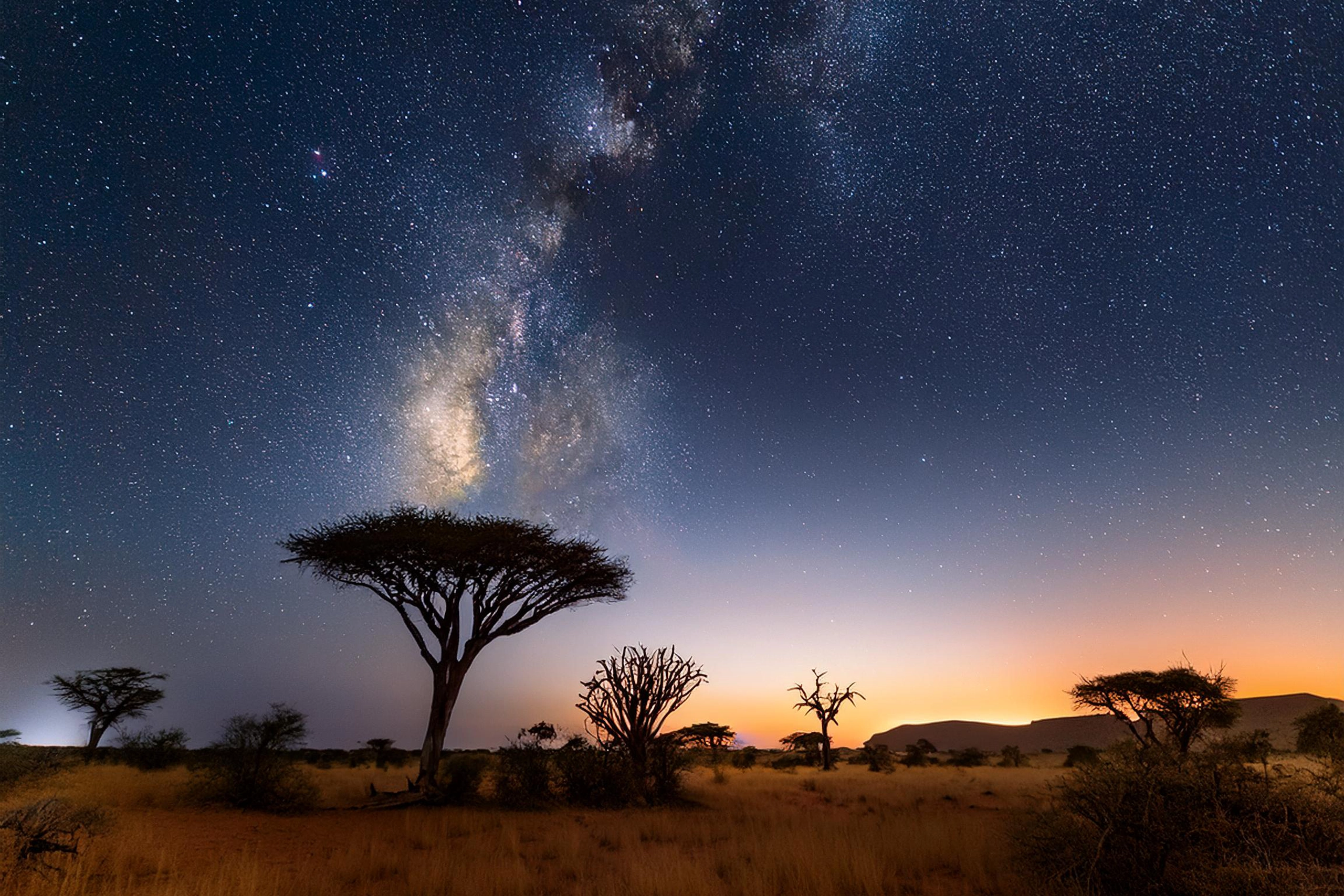 A breathtaking starry sky over the African landscape, showcasing the vastness and powerful energy of the night, reflecting the spiritual connection between nature and the universe