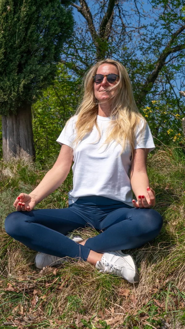 Tantra Person immersed in meditation in nature, surrounded by trees and soft light, embodying tantric presence and inner stillness