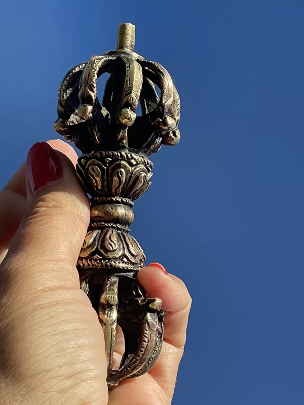 Tantra Vajra Dorje in close-up, a tantric symbol of enlightened mind, resting on a natural surface during an outdoor meditation session