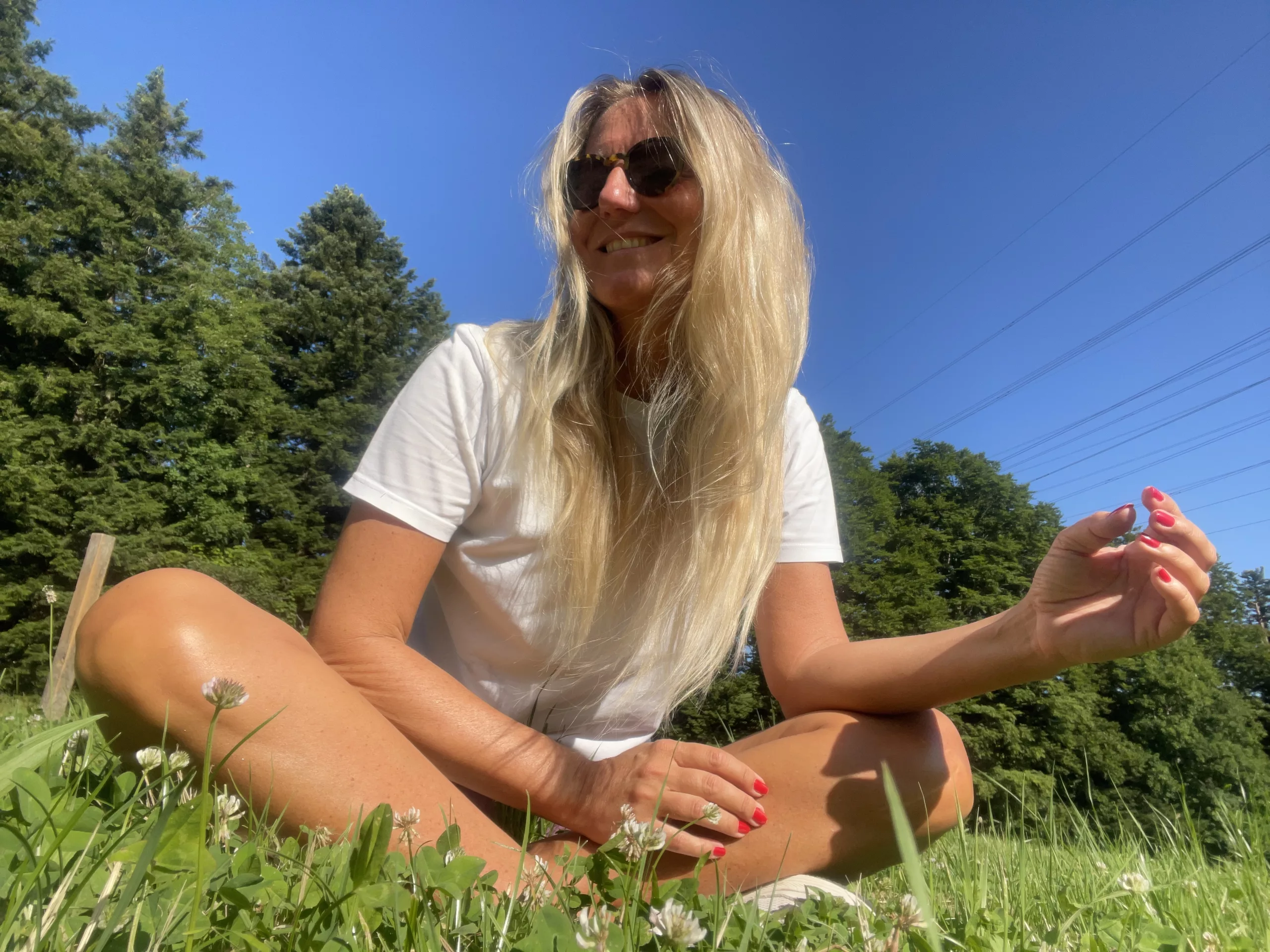 A person sitting on green grass surrounded by nature, with a peaceful and content smile, embodying harmony and simplicity