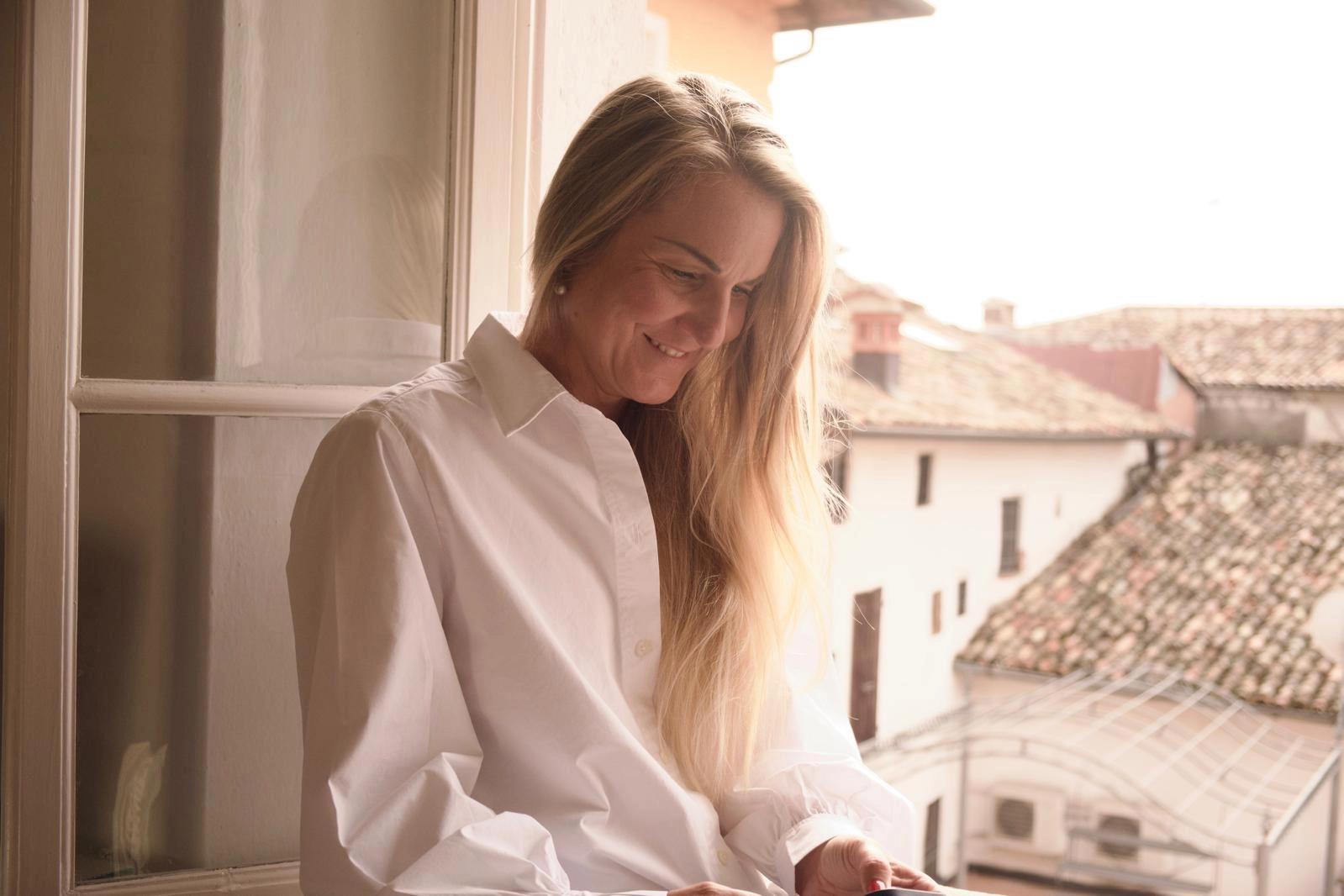 Portrait of a woman smiling while looking at her phone, radiating warmth and positivity